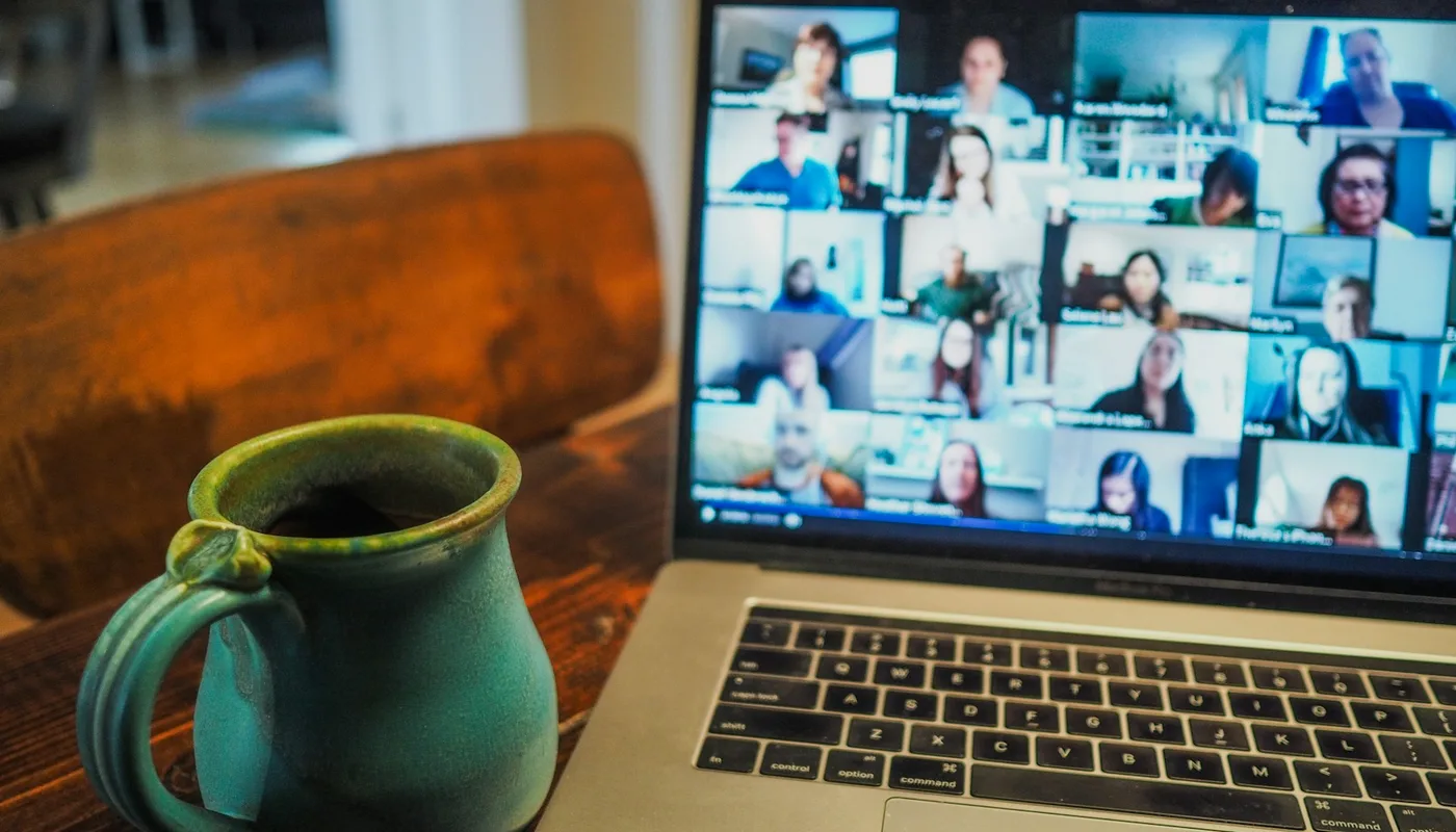 Laptop on a desk showing a remote video call with a distributed team